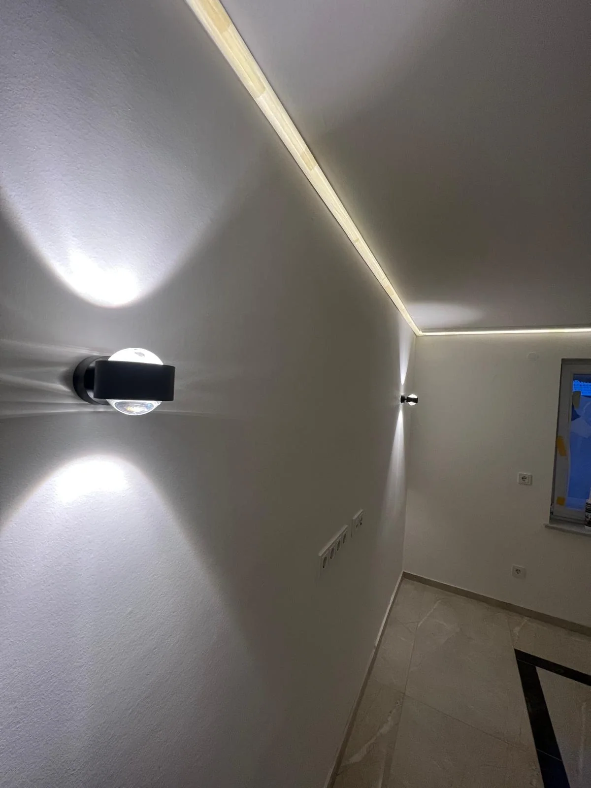 Indirekte LED-Lichtlinie und Wandleuchten in einem modernisierten Innenraum