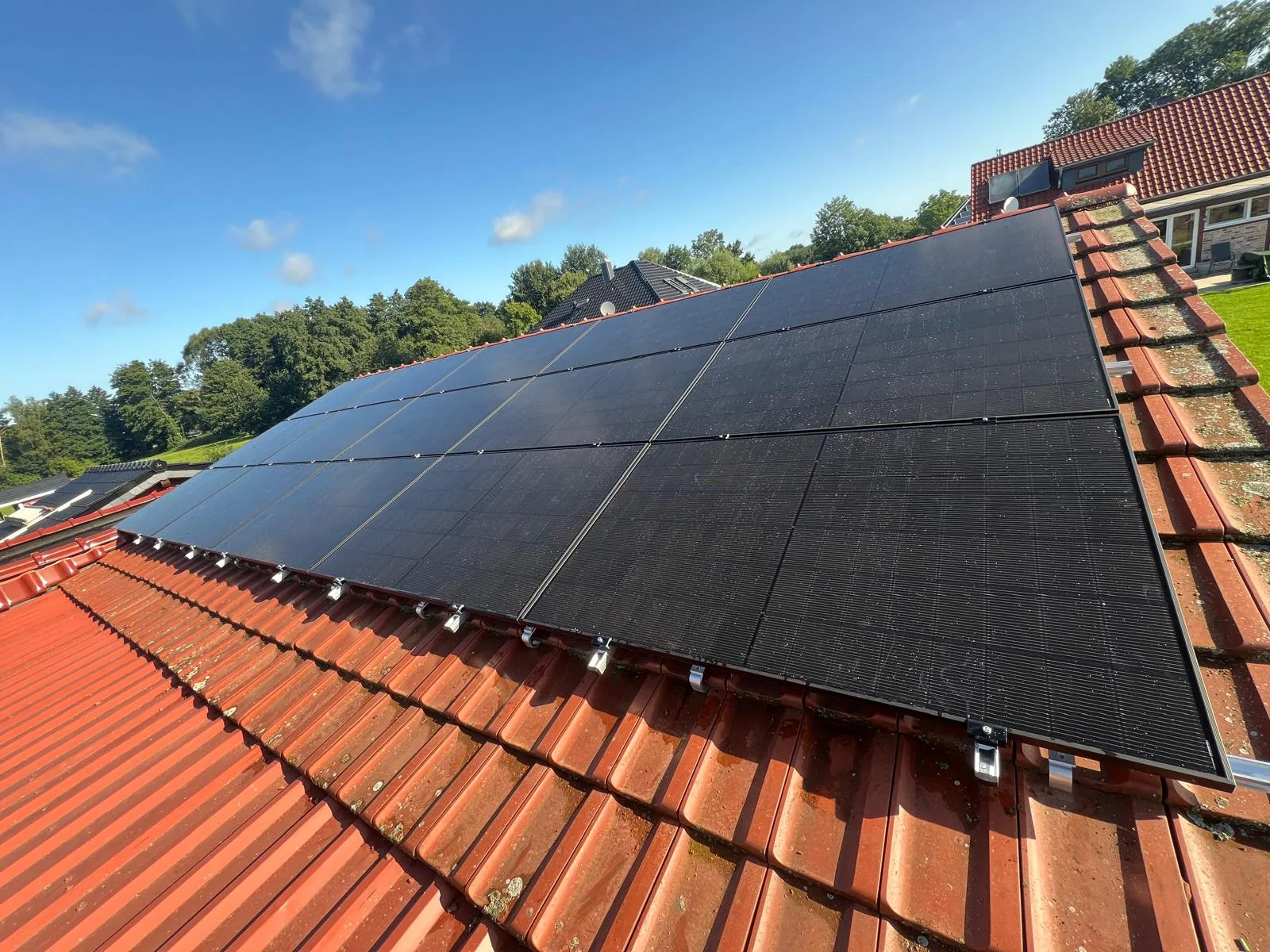Großflächige Photovoltaikanlage auf einem roten Hausdach