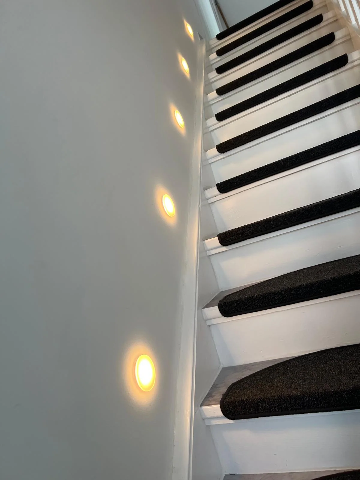 Runde warme LED-Spots als seitliche Beleuchtung einer Treppe